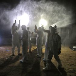 Hombres iraquíes con equipo de protección desinfectan sus trajes después de enterrar un cuerpo en un cementerio para víctimas de COVID-19, a 20 km de la ciudad sagrada central de Najaf. | Foto:Ali NAJAFI / AFP 