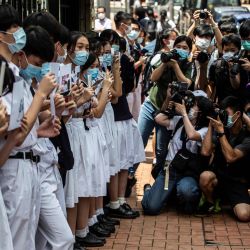 Los estudiantes de la escuela (L) sostienen carteles durante una protesta a favor de la democracia fuera de su escuela mientras los miembros de la prensa toman fotos en Hong Kong. | Foto:ISAAC LAWRENCE / AFP