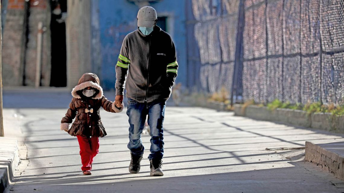 A child is accompanied by an adult as they walk in the the Villa 1-11-14 shanty town.