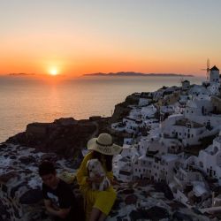 La gente mira la puesta de sol en la ciudad de Oia en la isla de Santorini mientras el país se prepara para el regreso de turistas a Grecia desde alrededor de 30 países por aire, mar y tierra. | Foto:ARIS MESSINIS / AFP