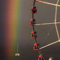 Los pasajeros se sientan en una rueda de la fortuna mientras aparece un arco iris durante la puesta de sol después de una lluvia en Hong Kong. | Foto:Anthony Wallace / AFP