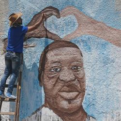El artista palestino Ayman al-Housari pinta un mural que representa a George Floyd, un hombre afroamericano desarmado que murió mientras estaba bajo custodia policial de Minneapolis, en la ciudad de Gaza. | Foto:MAHMUD HAMS / AFP