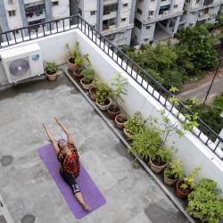 La instructora de yoga Pratibha Agarwal de Anahata Yoga Zone realiza posturas de yoga en la terraza de un edificio antes del Día Internacional de Yoga. | Foto:NOAH SEELAM / AFP