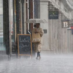 Una persona se refugia de la lluvia mientras son atrapados por un aguacero en Oxford Street en Londres, mientras las restricciones de cierre impuestas para detener la propagación del nuevo coronavirus continúan relajándose. | Foto:Tolga Akmen / AFP