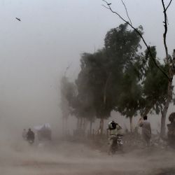 Un motociclista se cubre la cara durante una tormenta de polvo en Lahore. | Foto:Arif Ali / AFP