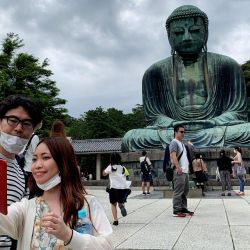 Una pareja con máscaras faciales se toma una selfie con la estatua del Gran Buda en el templo Kotoku-in en Kamakura. | Foto:Behrouz Mehri / AFP