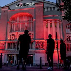 La gente se detiene para ver el lugar del evento Metropol iluminado en rojo durante la  | Foto:afp