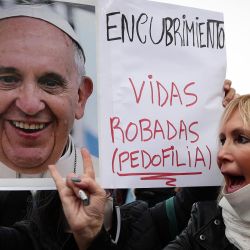 Una mujer grita consignas junto al manifestante con un cartel con una imagen del Papa Francisco que dice  | Foto:ALEJANDRO PAGNI / AFP