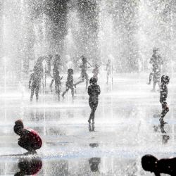 Los niños juegan bajo chorros de agua mientras se refrescan en las fuentes durante una ola de calor en la ciudad de Niza, en la costa francesa. | Foto:VALERY HACHE / AFP