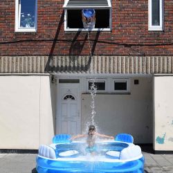 Kamila llena una piscina infantil arrojando agua desde una ventana de arriba sobre su hijo, Luca, de cinco años, mientras está parado en Hackney, al oeste de Londres. | Foto:JUSTIN TALLIS / AFP