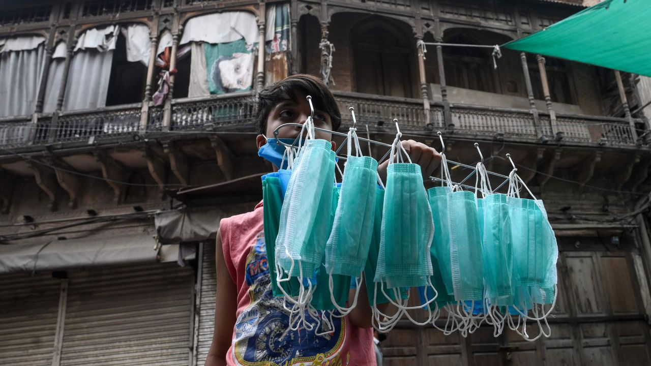 Un joven vendedor vende máscaras faciales en una calle cerca de un área restringida sellada por las autoridades en Lahore, ya que los casos de coronavirus COVID-19 continúan aumentando. | Foto:Arif Ali / AFP