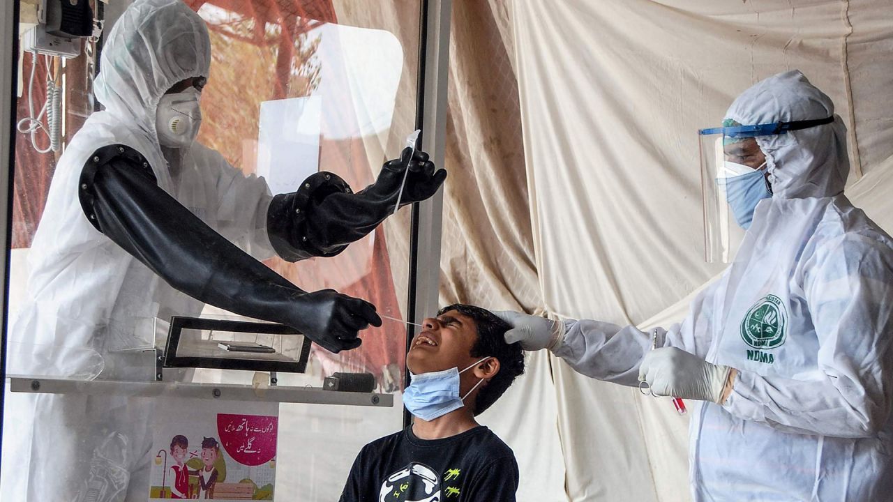 Los medicos toman una muestra de hisopo nasal de un niño en un centro de detección del coronavirus COVID-19, en Hyderabad. | Foto:STR / AFP