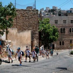 Los colonos israelíes con niños caminan por la calle cerrada palestina al-Shuhada bordeada de banderas israelíes en el área H2 de la ciudad de Hebrón. - Unos cientos de colonos judíos viven en el centro de la ciudad. Ciudad palestina de Hebrón que tiene una población de alrededor de 200,000. | Foto:HAZEM BADER / AFP
