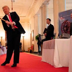 El presidente de los Estados Unidos, Donald Trump, se balancea con un bate de Texas Timber antes de hablar en un evento de exhibición del Spirit of America para destacar a las pequeñas empresas en el gran vestíbulo de la Casa Blanca, en Washington, DC. | Foto:JIM WATSON / AFP
