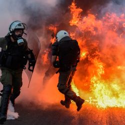 Agentes de la policía antidisturbios pasan frente a una barricada en llamas mientras se enfrentan con manifestantes durante una manifestación frente al parlamento para protestar contra la próxima ley del gobierno conservador para controlar las manifestaciones, en Atenas. | Foto:ARIS MESSINIS / AFP