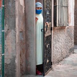 Una mujer se para detrás de su puerta en una calle cerrada después de que las autoridades marroquíes declararon un cierre total tras el descubrimiento de muchos casos de Covid-19 en una fábrica de conservas de pescado en la ciudad portuaria meridional de Safi. | Foto:FADEL SENNA / AFP