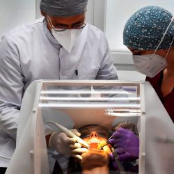 Un paciente recibe atención de un dentista protegido por un plexiglás y un escudo de silicona contra el nuevo coronavirus (COVID-19), creado por la compañía Occisphere en Toulouse, sur de Francia. | Foto:GEORGES GOBET / AFP