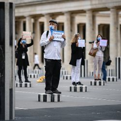 Los guías turísticos de París sostienen pancartas en protesta por sus condiciones de trabajo debido al brote de la nueva enfermedad del coronavirus (COVID-19), mientras se paran en las columnas de The Colonnes de Buren (Les deux Plateaux), una instalación de arte del artista francés Daniel Buren en el patio interior de los jardines del Palacio Real de París. | Foto:Anne-Christine Poujoulat / AFP
