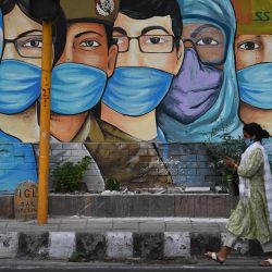 Una mujer camina junto a un mural de trabajadores de primera línea después de que el gobierno alivió un bloqueo nacional impuesto como medida preventiva contra el coronavirus COVID-19 en Nueva Delhi. | Foto:Sajjad Hussain / AFP