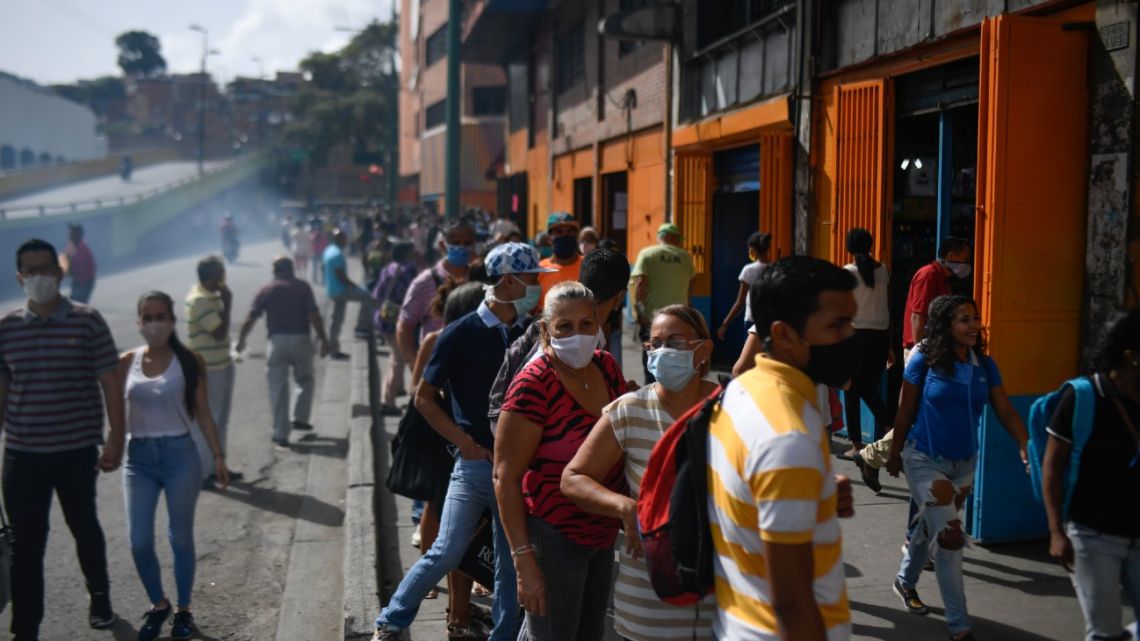 People wear face masks as they line up to buy groceries outside a supermarket at the Petare neighbourhood in Caracas, on July 13, 2020, after the government eased a nationwide lockdown imposed as a preventive measure against the Covid-19 coronavirus. 