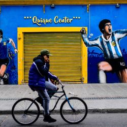 Un hombre monta su bicicleta frente a una tienda deportiva cerrada en el barrio de La Boca en Buenos Aires, en medio de la nueva pandemia de coronavirus. - El barrio de La Boca en Buenos Aires se ha visto muy afectado por la falta de turistas debido a la pandemia. | Foto:RONALDO SCHEMIDT / AFP