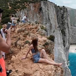 Los turistas toman fotos y selfies desde una roca con vista a la famosa playa de Navagio (Naufragio) en la isla jónica de Zakynthos. - Por lo general, para la temporada, hay 20 salidas diarias a la playa histórica de la isla, ahora solo cuatro operan diariamente. | Foto:Louisa Gouliamaki / AFP