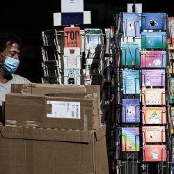 Un trabajador con una mascarilla protectora debido a la pandemia del coronavirus COVID-19, pasa junto a las postales que se muestran fuera de una tienda en Burdeos, suroeste de Francia. (Foto de Philippe LOPEZ / AFP) | Foto:afp