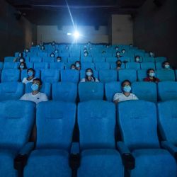 La gente mira una película mientras se sientan por separado para el distanciamiento social en un cine en Hangzhou, en la provincia oriental china de Zhejiang, el primer día que los cines reabrieron después del cierre causado por el brote de coronavirus COVID-19. | Foto:STR / AFP
