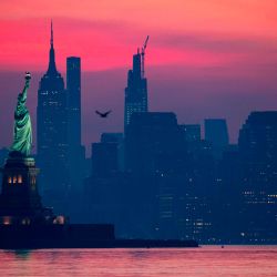 La Estatua de la Libertad se muestra frente al Bajo Manhattan antes del amanecer en medio de la pandemia de coronavirus en la ciudad de Nueva York. | Foto:Johannes Eisele / AFP