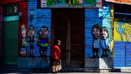 Una mujer pasa frente a un restaurante cerrado en el barrio de La Boca en Buenos Aires, en medio de la nueva pandemia de coronavirus. - El barrio de La Boca en Buenos Aires se ha visto muy afectado por la falta de turistas debido a la pandemia.