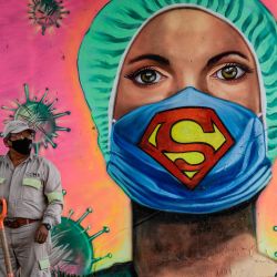 Un jardinero de la ciudad trabaja junto a un mural que muestra a un trabajador de la salud con una máscara facial con el símbolo del superhéroe ficticio Superman, firmado por el artista urbano Applez, en la Ciudad de México, en medio de la nueva pandemia de coronavirus de COVID-19. | Foto:Pedro Pardo / AFP