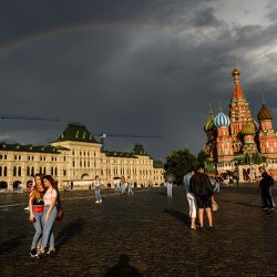 La gente camina frente a la Catedral de San Basilio iluminada por el sol con un arcoíris de fondo en la Plaza Roja de Moscú. | Foto:Dimitar Dilkoff / AFP