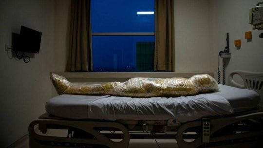 El cuerpo de una presunta víctima de Covid-19 yace en un hospital indonesio. Después de la muerte del paciente, las enfermeras del hospital envolvieron el cuerpo inerte en capas de plástico y aplicaron desinfectante para evitar la propagación del virus.