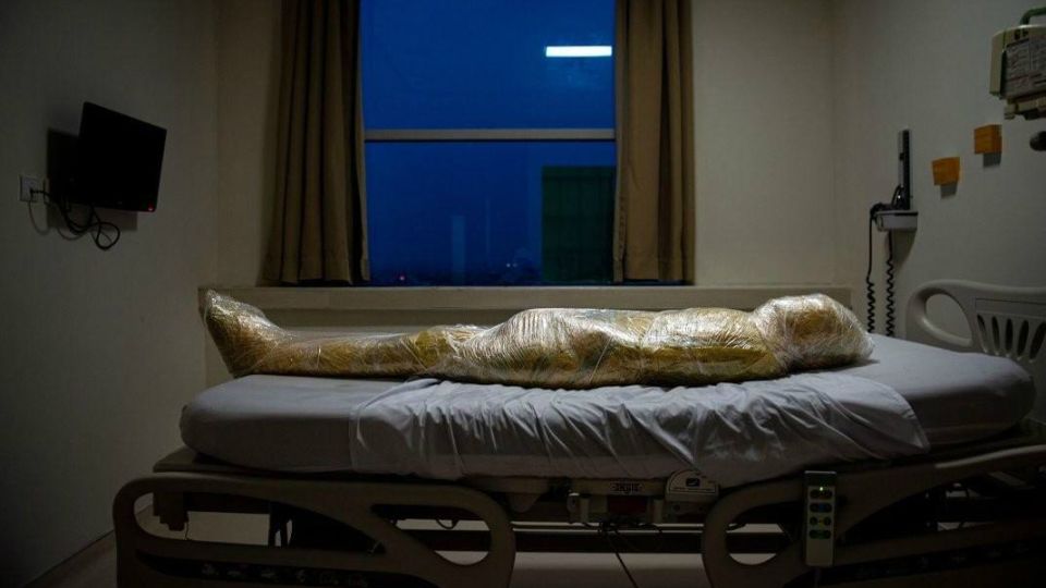 El cuerpo de una presunta víctima de Covid-19 yace en un hospital indonesio. Después de la muerte del paciente, las enfermeras del hospital envolvieron el cuerpo inerte en capas de plástico y aplicaron desinfectante para evitar la propagación del virus.