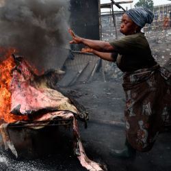 Una mujer arroja piel de vaca al fuego para quemar la cubierta exterior peluda en un matadero en Kara, estado de Ogun, en el suroeste de Nigeria. | Foto:PIUS UTOMI EKPEI / AFP