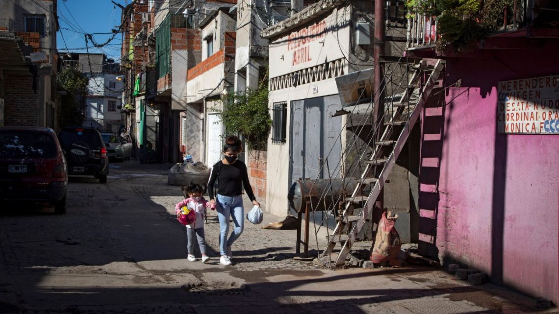 A woman and a girl walk along an alley at the Padre Carlos Mugica neighbourhood, also known as Villa 31 shantytown, in Buenos Aires, on July 25, 2020, amid a lockdown against the spread of the new coronavirus. 