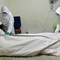 Trabajadores de funerarias se preparan para llevar el cadáver de un hombre que presuntamente murió de COVID-19 desde su casa en Cali, Colombia. | Foto:Luis Robayo / AFP
