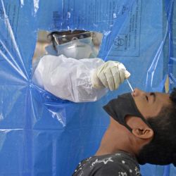 Un trabajador de la salud con traje de equipo de protección personal (PPE) recolecta una muestra de un residente en un centro de prueba gratuito para el coronavirus COVID-19, en Hyderabad. | Foto:NOAH SEELAM / AFP