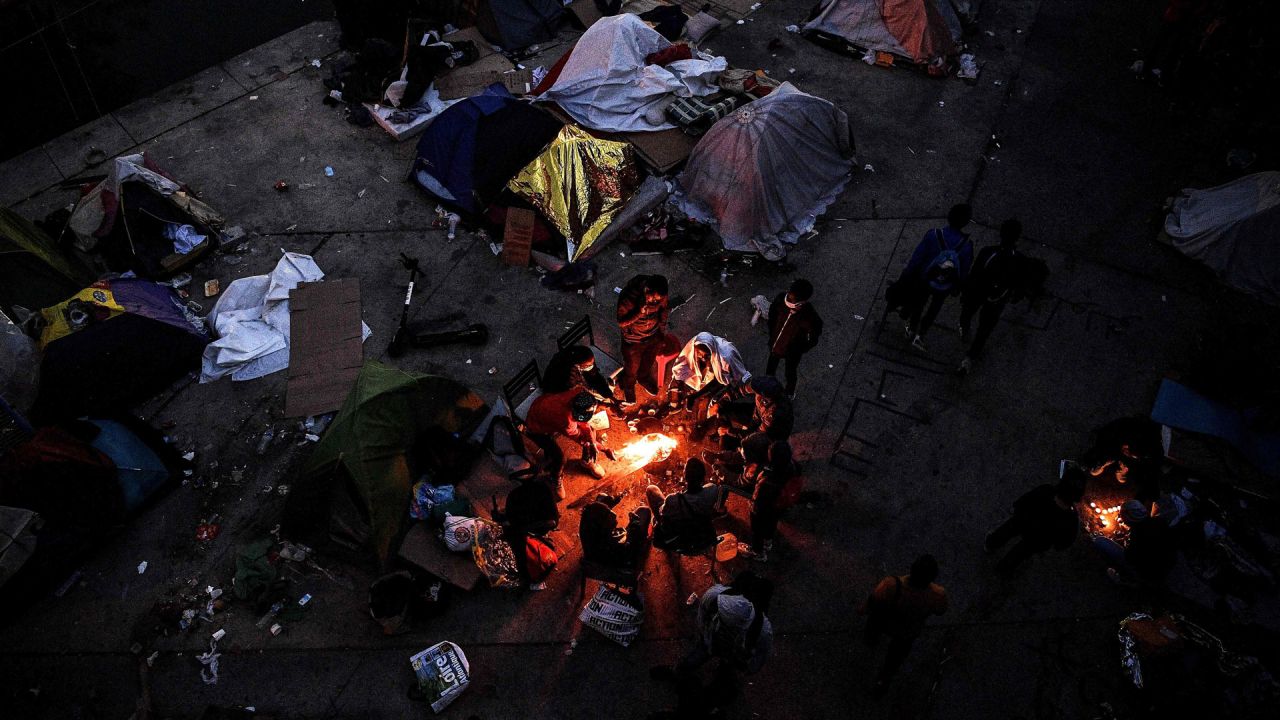 Los solicitantes de asilo se calientan alrededor de una hoguera antes de su evacuación de un campamento improvisado ubicado a lo largo del Canal Saint-Denis en Aubervilliers cerca de París. | Foto: Christophe Archambault / AFP