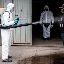 Un trabajador municipal desinfecta a un guardia de seguridad en Villa María del Triunfo, en las afueras del sur de Lima. | Foto:ERNESTO BENAVIDES / AFP