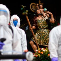 Los trabajadores municipales en traje de protección se preparan para desinfectar un automóvil fuera de una iglesia durante la celebración del Día de San Cristóbal, patrón de viajeros y conductores, en la Ciudad de Guatemala en medio de la pandemia de coronavirus COVID-19. | Foto:Johan Ordonez / AFP