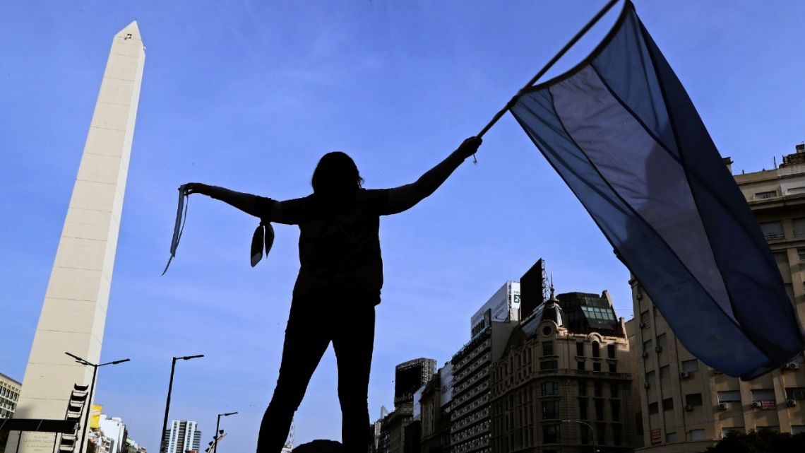 A woman waves an Argentine flag during a protest against the government's judicial reform bill at the Obelisk in downtown Buenos Aires, on August 1, 2020