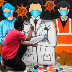Un artista da los toques finales a un mural que representa a los trabajadores de primera línea durante un cierre completo de un día impuesto por el gobierno estatal contra el aumento de los casos de coronavirus COVID-19 en Kolkata. | Foto:Dibyangshu Sarkar / AFP