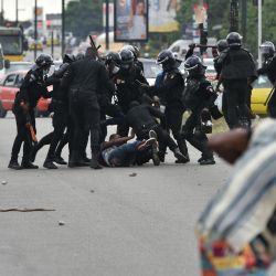 Los policías golpearon a un manifestante durante una manifestación de los partidarios del ex presidente de Costa de Marfil Laurent Gbagbo para protestar contra su ausencia en la lista electoral de los candidatos presidenciales, cerca de la sede de la comisión electoral en el bulevar Latrille en el distrito Cocody de Abidjan. | Foto:SIA KAMBOU / AFP