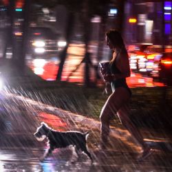 Una mujer corre con su perro durante una fuerte lluvia en Miami Beach, Florida, en medio de la pandemia de coronavirus. - Se emitió un aviso de inundación para una parte del condado de Broward debido a las fuertes lluvias. | Foto:CHANDAN KHANNA / AFP