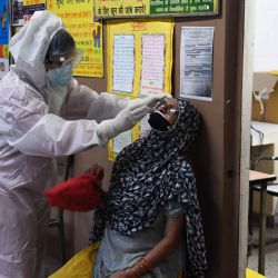 Un personal médico recolecta una muestra de una mujer para la prueba rápida de antígeno para el coronavirus COVID-19 en un dispensario del gobierno en Nueva Delhi. | Foto:Prakash Singh/ AFP