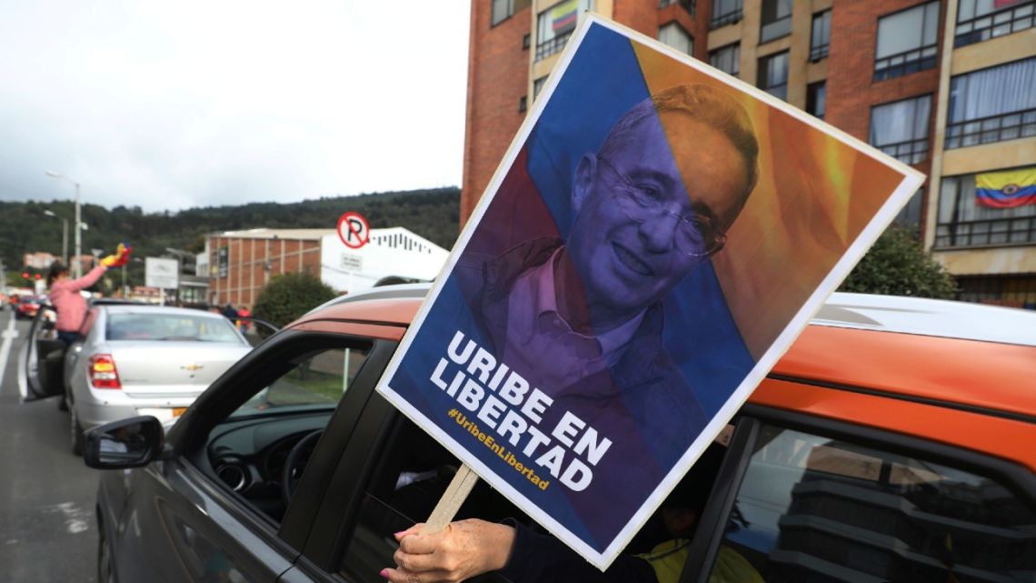 A supporter of former president Alvaro Uribe holding a banner with an image of him with a message that reads in Spanish: "Free Uribe", takes part in caravan to protest the Supreme Court decision to place Uribe under house arrest while it advances a witness tampering investigation against him, in Bogotá, Colombia, Friday, Aug. 7, 2020.