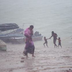 Un devoto hindú con sus hijos camina en la orilla del Sangam para darse un baño sagrado durante las fuertes lluvias en Allahabad. | Foto:SANJAY KANOJIA / AFP