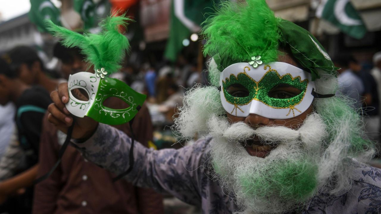 Un vendedor con una máscara con los colores de la bandera nacional de Pakistán sostiene otra máscara mientras espera a los clientes en un mercado en Karachi, antes del 74o Día de la Independencia del país, que marca el fin del dominio colonial británico. | Foto:Asif Hassan / AFP