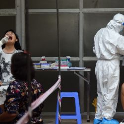 Los trabajadores de la salud que usan ropa protectora toman una prueba de hisopo para el coronavirus COVID-19 en dos residentes del centro médico del distrito de Hoan Kiem en Hanoi. | Foto:Nhac Nguyen / AFP